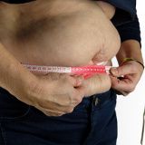 Abdomen de una persona con sobrepeso rodeado con una cinta métrica