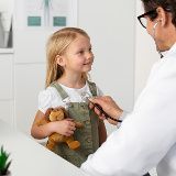 Médico auscultando a una niña pequeña