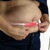 Abdomen de una persona con sobrepeso rodeado con una cinta métrica